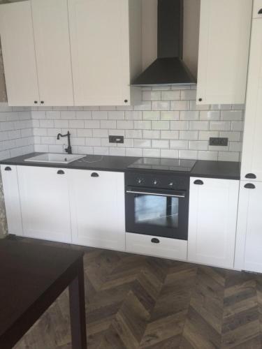 a kitchen with white cabinets and a sink and a stove at Luxury Apartment in Druskininkai