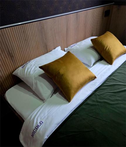 a bed with four pillows on top of it at Garni Hotel & Spa Nicolo in Kruševac
