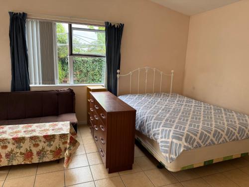 a bedroom with a bed and a dresser and a window at Lilys guest house in Auckland