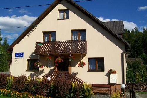 a house with a balcony with flowers on it at Apartament i Pokoje Gościnne u Lusi in Wisła