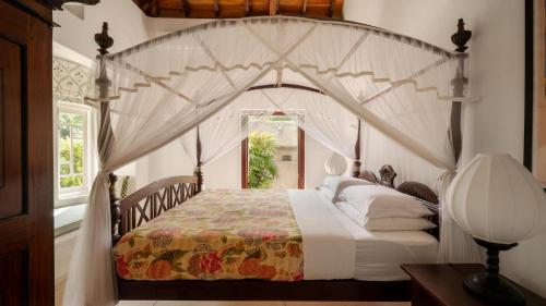 a bedroom with a large bed with a canopy at Coconut Grove - 4 Bed Pool Villa with Cook in Ahangama
