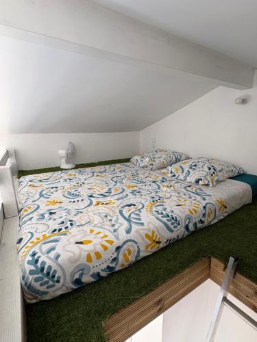 a bedroom with a bed with a colorful comforter at Studio cosy avec piscine à 10 min Hossegor in Saint-Vincent-de-Tyrosse
