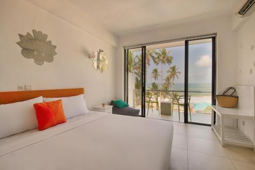 a bedroom with a bed and a view of the ocean at Mask & Tide - Jetwing Select in Ambalangoda