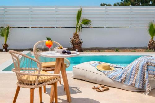 a table and chairs next to a pool at Meltemi Blu - Adults Only in Perissa