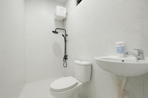 a white bathroom with a toilet and a sink at Arumi Experience Tasikmalaya Syariah in Tasikmalaya
