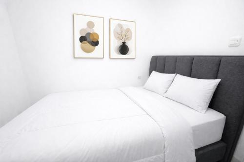 a bedroom with a white bed with two pictures on the wall at Arumi Experience Tasikmalaya Syariah in Tasikmalaya