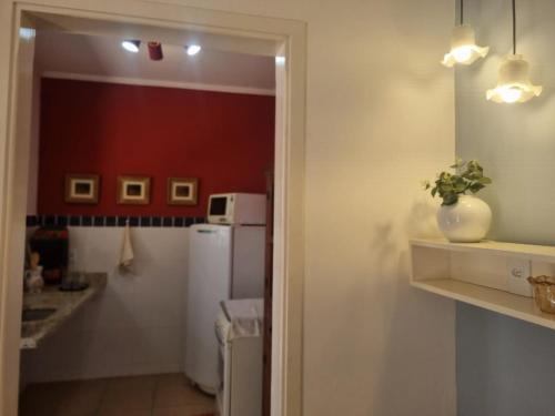 a kitchen with a white refrigerator and a red wall at Costa Family-Little house in the center in Santa Rita do Sapucaí