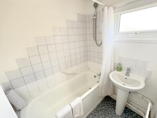 a white bathroom with a tub and a sink at Large 2 bedroom house in Wombridge