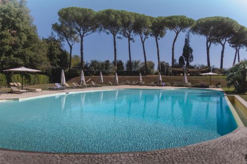 a swimming pool with chairs and trees in the background at Borgo di Colleoli Resort in Colleoli