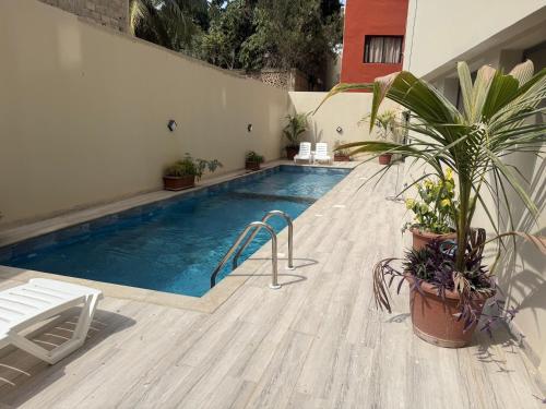 a swimming pool with potted plants next to a building at Sublime appartement avec Piscine, 2 chambres au Point E, Dakar in Dakar