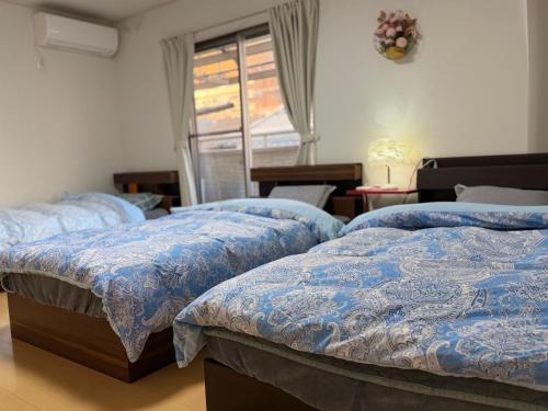 a bedroom with three beds with blue comforters and a window at 孔雀民宿 in Osaka