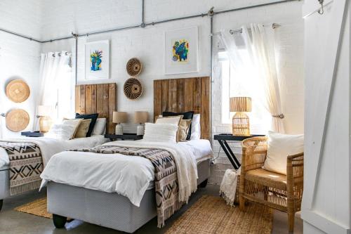 a bedroom with two beds and a chair at The Bay Cottage in Pringle Bay