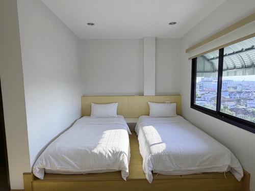 two beds in a room with a window at Klongrien Boutique Hotel in Hat Yai