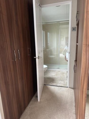 a bathroom with a glass door leading to a toilet at Aurora luxury beach lodge in Lossiemouth