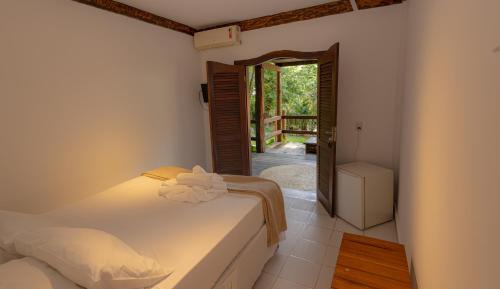 a bedroom with two beds and a door to a balcony at Casa La Luna - Arraial D'Ajuda in Arraial d'Ajuda