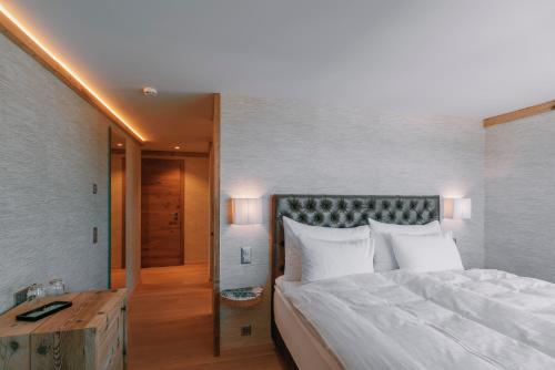 a bedroom with a large white bed and a desk at Caschu Alp Boutique Design Hotel Stoos - adults only in Stoos