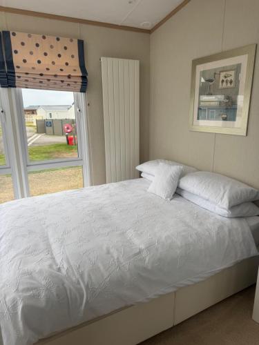 a bedroom with a white bed with a window at Aurora luxury beach lodge in Lossiemouth