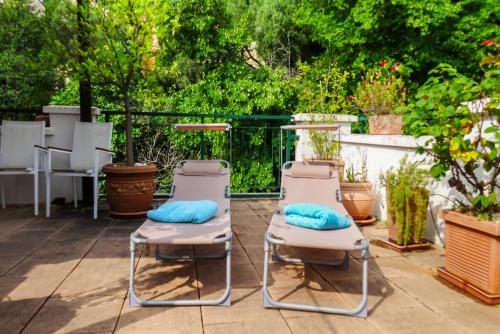 two lounge chairs with blue pillows on a patio at Lisa's Stylish Top Floor Flat & Double Pool in Pietra Ligure