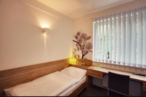 a room with a bed and a desk and a window at GREEN HOTEL Ostrava in Jáma František