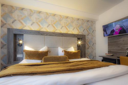 a bedroom with a large bed with a tv on the wall at Hotel Zur Feldmühle in Arnsberg
