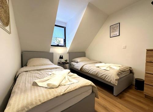two beds in a attic bedroom with a window at ODA Living Lüneburg in Lüneburg