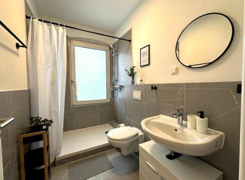 a bathroom with a sink and a toilet and a mirror at ODA Living Lüneburg in Lüneburg