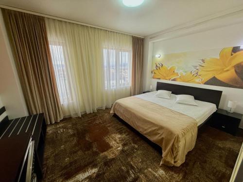 a bedroom with a bed and a painting on the wall at Hotel Grandis Apulum in Mioveni