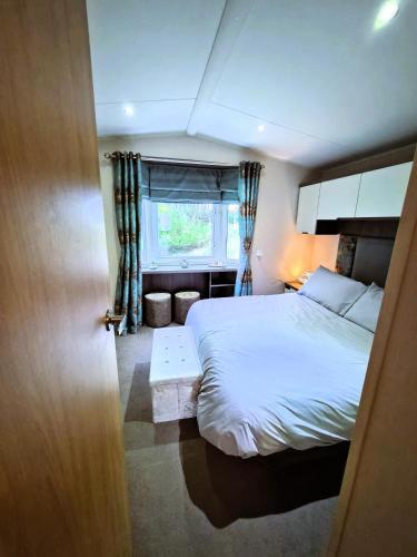 a bedroom with a large bed and a window at Sylvia's Sunrise Caravan Skegness Southview in Winthorpe