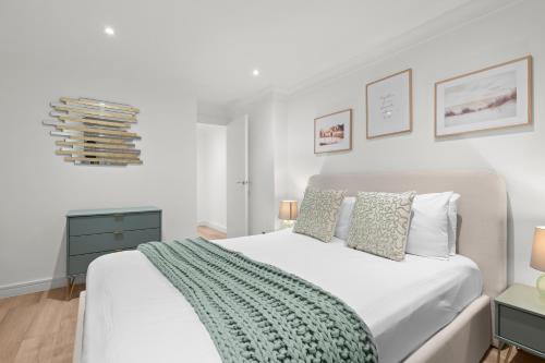 a bedroom with a white bed with a green blanket on it at Hyde Park Apartments - Prime Vision Living London in London