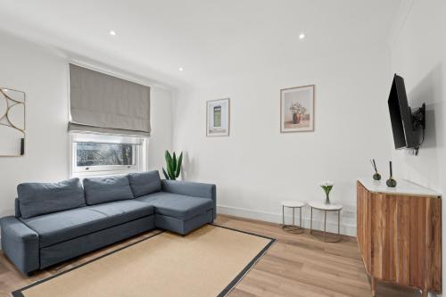 a living room with a blue couch and a tv at Hyde Park Apartments - Prime Vision Living London in London