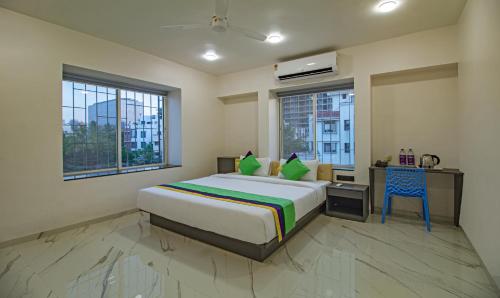a bedroom with a bed and a desk and two windows at Treebo Atithi Comforts Inn in Pune