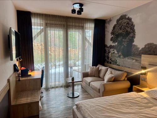 a bedroom with a bed and a couch and a window at Hotel Erve Hulsbeek in Oldenzaal