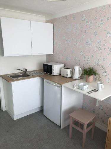 a kitchen with white cabinets and a counter top at Basingstoke En Suite Room in Garden Annex in Basingstoke