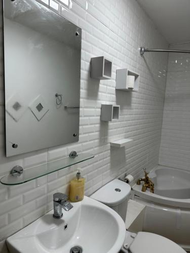 a bathroom with a sink and a toilet and a mirror at Double bed room like a hotel room with share toilet in Hyde