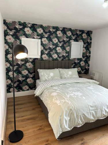 a bedroom with a bed with floral wallpaper at Double bed room like a hotel room with share toilet in Hyde