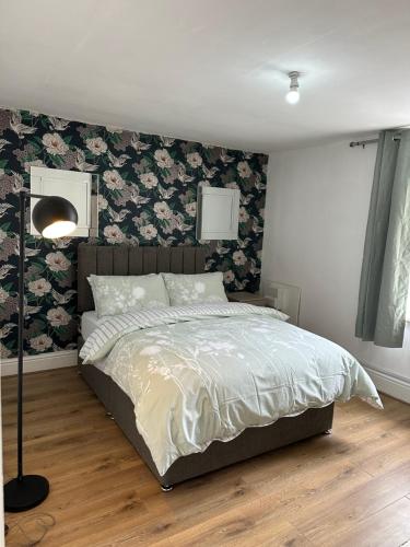 a bedroom with a bed with floral wallpaper at Double bed room like a hotel room with share toilet in Hyde