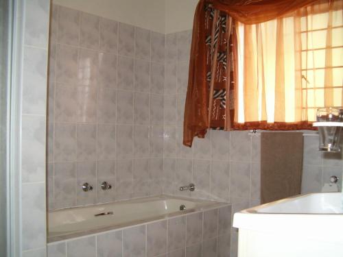 a bathroom with a bath tub and a window at Ingwe Guest lodge in Vanderbijlpark