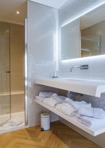 a bathroom with a sink and a mirror and towels at Hôtel le XIX in Béziers