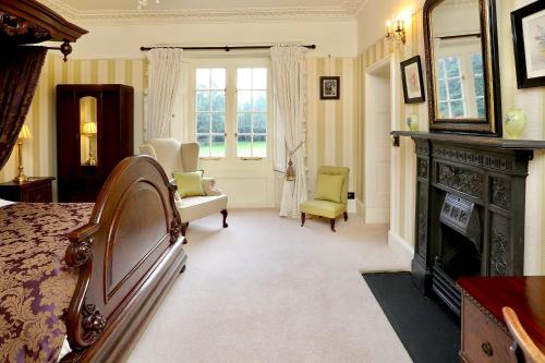 a bedroom with a fireplace and a bed and chairs at Llangattock Park House in Crickhowell