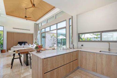 a kitchen with wooden cabinets and a living room at SHAMBHALA GRAND Pool Villas x MonthStayZ Thailand in Phuket
