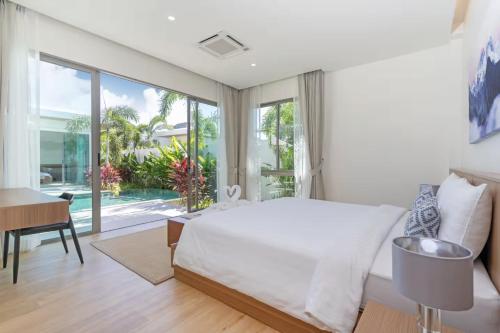 a bedroom with a large white bed and a desk at SHAMBHALA GRAND Pool Villas x MonthStayZ Thailand in Phuket