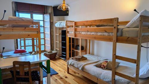 a room with bunk beds and a table and a desk at Lagarto Pintado Casa n'Aldeia in Castelo Novo
