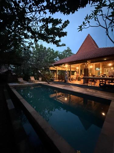 a swimming pool in front of a house at night at The Secreet Garden Hotel in Denpasar
