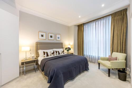 a bedroom with a large bed and a chair at Buckingham & Lloyds Knightsbridge in London
