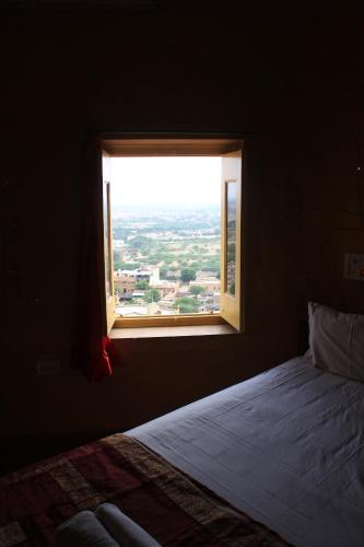 a bedroom with a window with a view of a city at Mud Mirror Guesthouse in Jaisalmer