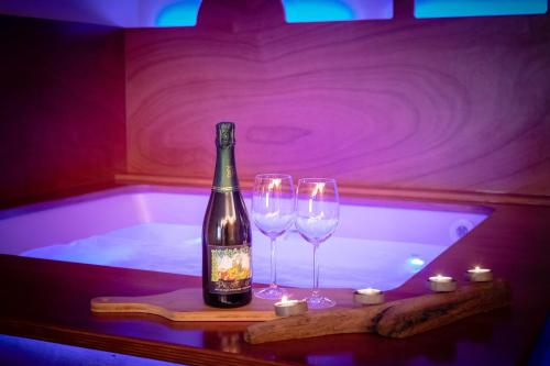 a bottle of wine and two wine glasses in a bath tub at Hotel Beau Sejour Pré-Saint-Didier in Pré-Saint-Didier