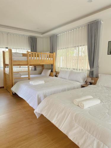 a bedroom with two bunk beds with white sheets at Chaisona at Khanom Storey in Ban Phaeng