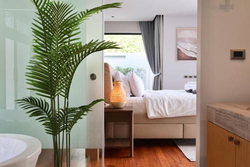 a bedroom with a bed and a palm plant at Botanica - Bali Style Luxury 3 BR Private Pool Villa in Ban Pak Lak