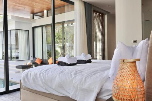 a bedroom with a large bed with white sheets and pillows at Botanica - Bali Style Luxury 3 BR Private Pool Villa in Ban Pak Lak