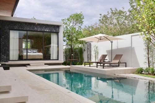 a pool with a table and an umbrella next to a house at Botanica - Bali Style Luxury 3 BR Private Pool Villa in Ban Pak Lak